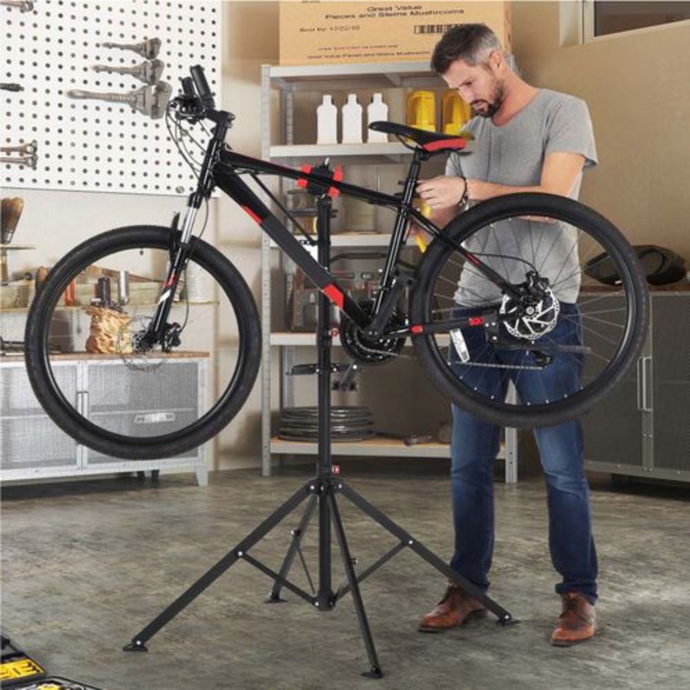Man working on a bike held in a repair stand in a home garage