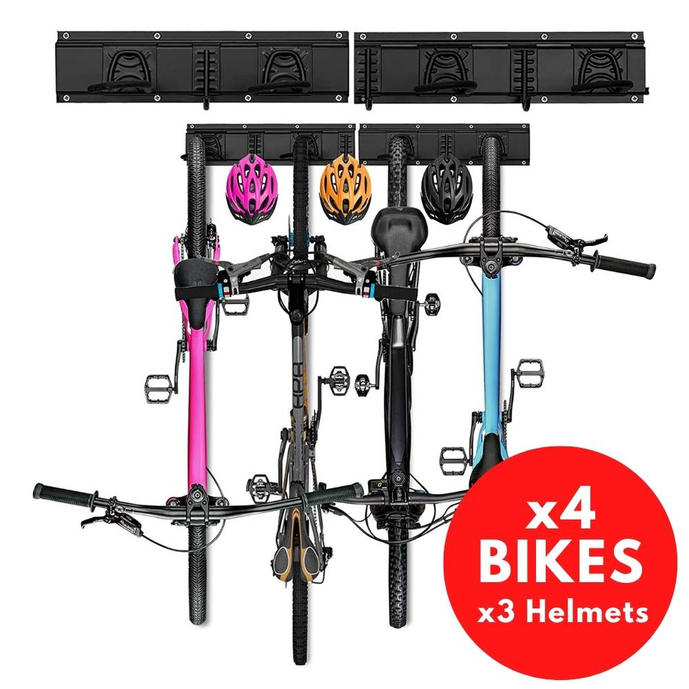 Four bikes hanging upright from a wall rail with helmets on the spare hooks