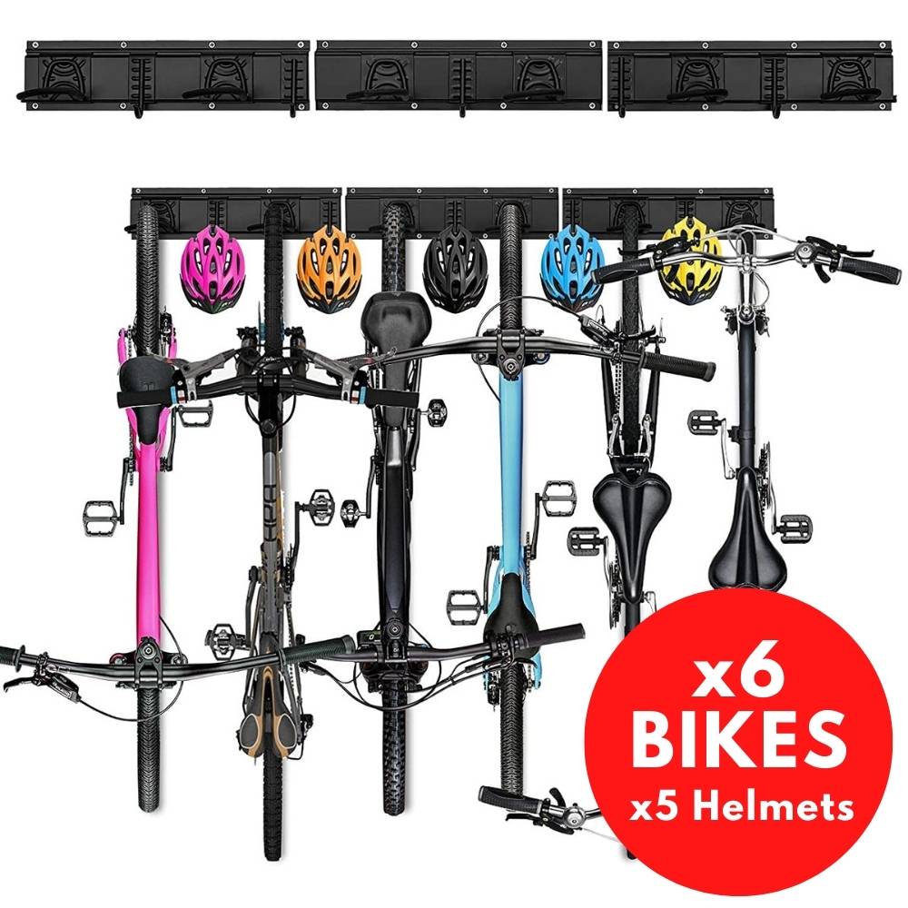 Six bikes hanging upright from a wall rail with helmets on the spare hooks