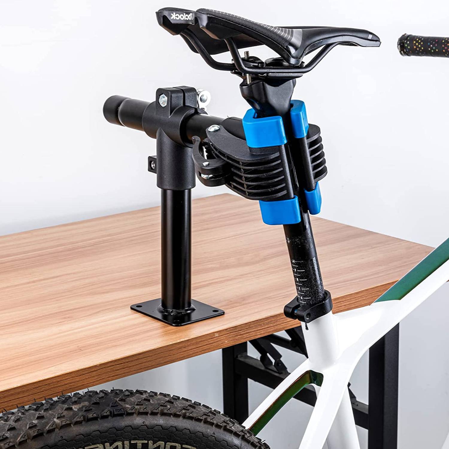Repair clamp fixed to a wooden bench, holding a bike by its seatpost